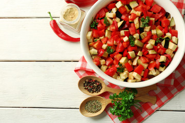 Ratatouille before cooking and ingredients, on wooden background