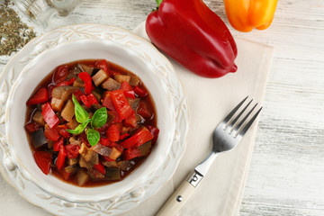Ratatouille in bowl, on wooden table background