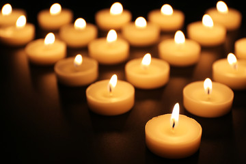 Obraz na płótnie Canvas Alight candles in a row on black background