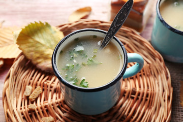 Mug of soup on wicker mat