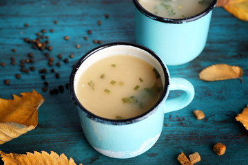 Two mugs of soup on blue wooden background