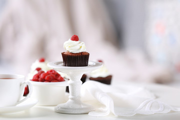 Beautiful chocolate cupcakes with cream and raspberry on table