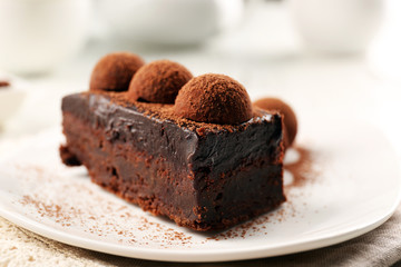 Slice of chocolate cake with a truffle on plate closeup