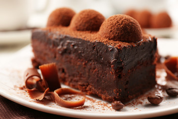 Slice of chocolate cake with a truffle on plate closeup