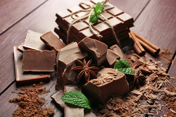 Variety of chocolate pieces, coffee grains and cocoa powder on wooden background
