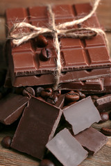Milk chocolate pieces and coffee grains on wooden background