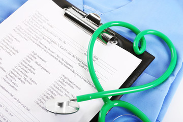 Heart shaped stethoscope with medical record on blue uniform, close up