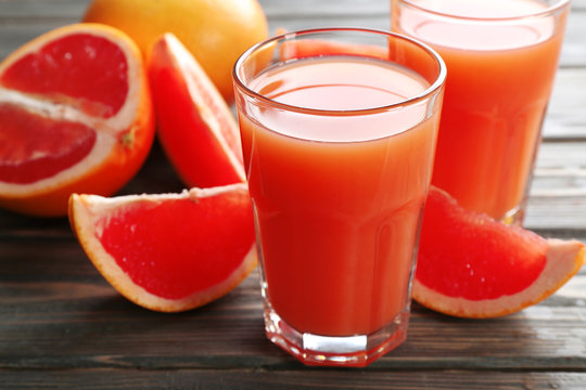Glass of grapefruit juice and fresh fruits on wooden background