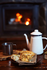 Teapot and mugs on vintage wooden table. Fireplace as background