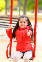Little girl on swing in city park