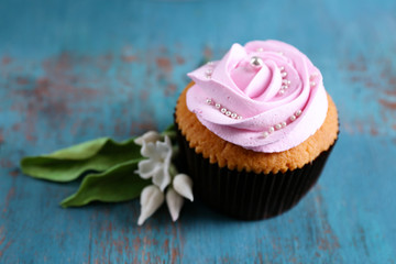 Tasty cupcake on color wooden background