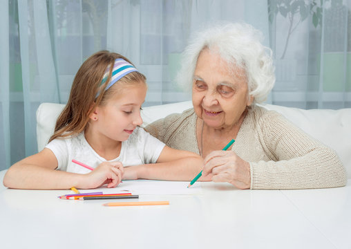 little girl and her grandmother drawing with pencils