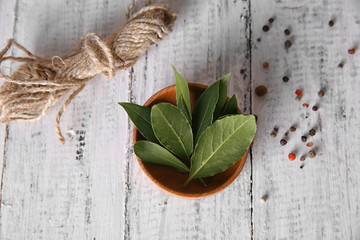 Fresh bay leaves in bowl on white wooden table