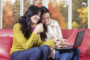 Women using laptop at home with autumn background