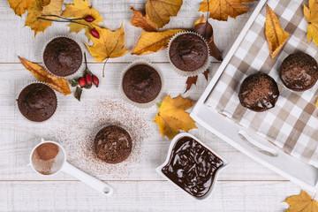 Vintage food background with delicious homemade chocolate muffins on white wooden table. Autumn and winter theme.