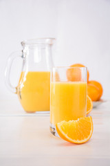 Fototapeta na wymiar Orangensaft mit halbierter Orange und Orangenvierteln