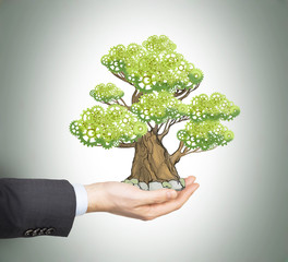 A hand in formal suit holds a sketched tree on the palm. Light grey background. A concept of the...