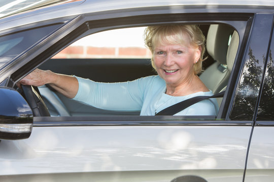 Portrait Of Smiling Senior Woman Driving Car