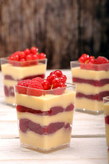 Pudding in a glass with fresh raspberries and currants on white