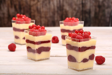 Pudding in a glass with fresh raspberries and currants on white
