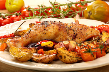 Roasted chicken legs with vegetables and herbs on wooden backgro
