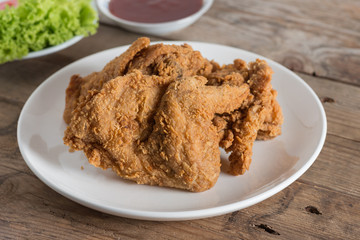 Fried chicken in white plate on a wood table.
