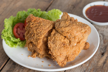 Fried chicken in white plate on a wood table.