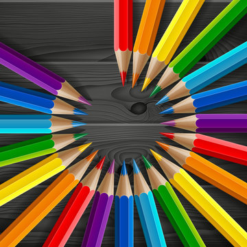 Circle of rainbow colored pencils with realistic shadows on dark grey wood texture background