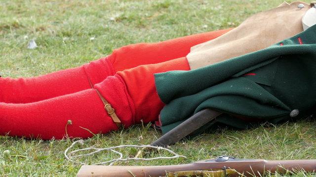 One guard in red socks is lying on the grass. He is wearing the gray and red uniform