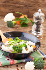 Healthy cauliflower and broccoli soup on rustic table, vertical