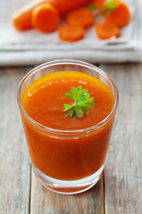 Fresh carrot juice in glass on wooden table, healthy vegetable drink