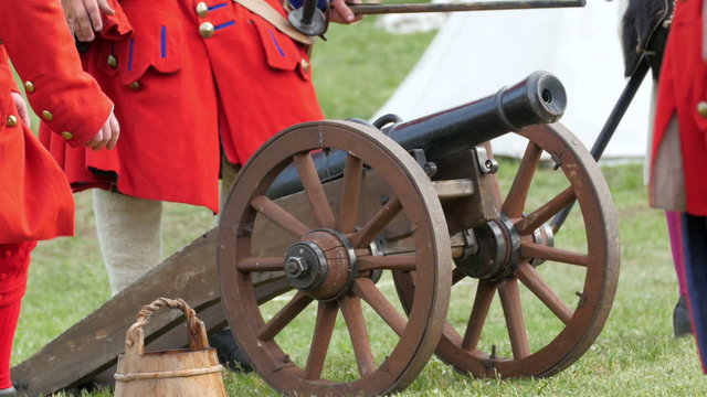 Guards walking away from the cannon after firing. One guard is pulling up the cannon