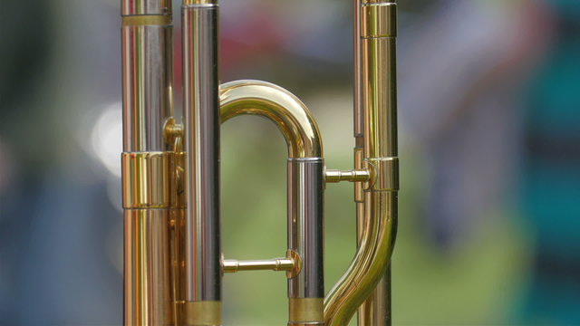 A trombone standing on the table. The gold shiny trombone is one of the instrument used in the concert
