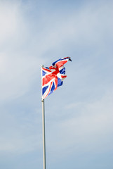 Flag of Great Britain. Color photo, blue sky with clouds background.