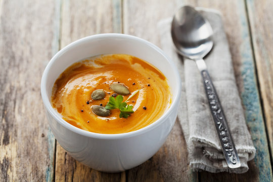 Fresh carrot soup in white bowl, dietary vegetable soup, rustic style