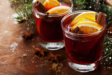 Christmas mulled wine or gluhwein with spices and orange slices on rustic table, traditional drink...