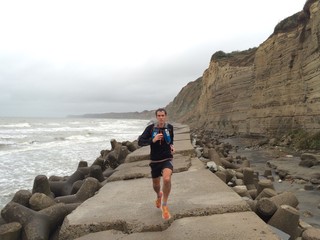 Male runner running along sea defences