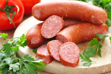 Smoked sausage with spices and vegetables on wooden table
