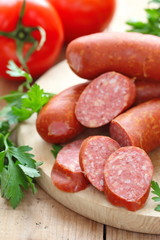 Smoked sausage with spices and vegetables on wooden table