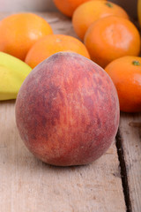 Bananas apple mandarin peach strawberry on wooden background as health food concept