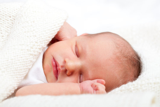 Newborn baby girl sleeping on a white blanket