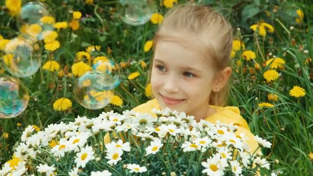Closeup portrait girl and huge bouquet of white flowers. Child looking at camera and smiling. Soap bubbles flying. Thumbs up. Ok