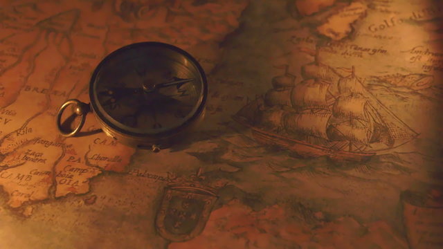 A compass and the map on a dim light. With the yellow light on the background