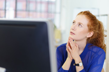 frau im büro schaut nachdenklich nach oben