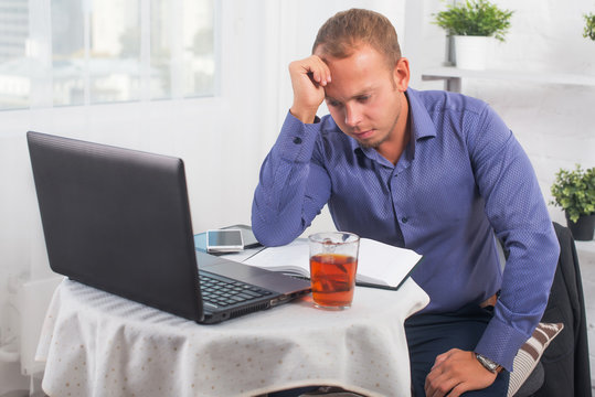 Young businessman working in the office, very concerned, solves problem, and leaned head on his hand.