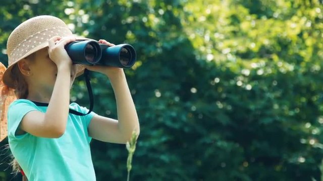 Closeup portrait girl looking through binoculars at camera and waving hand and laughing