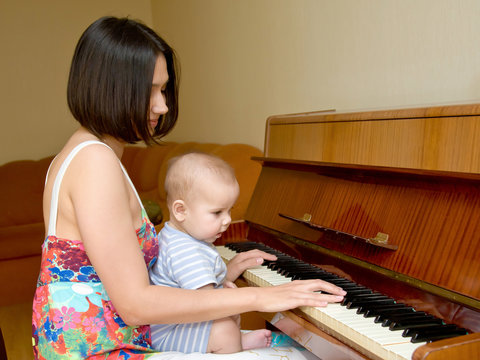mother teaching baby to play the piano.