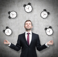 Meditative businessman is pondering about time management. The person in formal suit is surrounded...