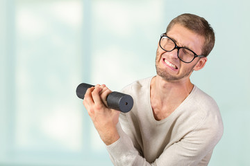 Naklejka premium Funny weak man tries to lift a weight
