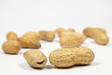 Two peanuts in shell in front of other ones, on white background